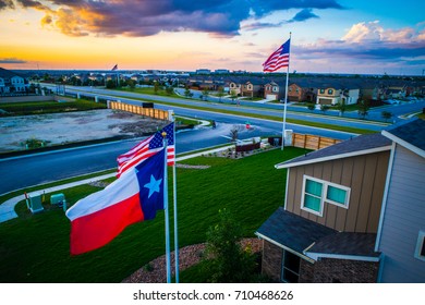 Texas Flag In The Foreground With American Flag High In The Background With New Home About To Hit The Market In Austin Texas USA Aerial Drone View Of New Suburb Development Perfect Living In America