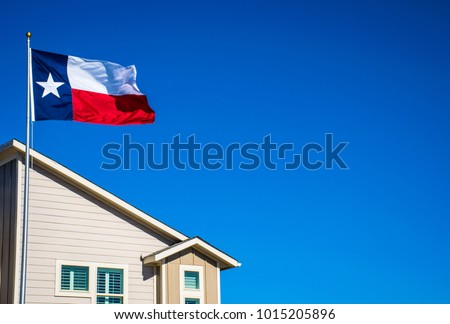 Texas flag on perfect flagpole flying in front of brand new modern home in new suburb in Austin , Texas the capital city of Texas in the Lone Star State