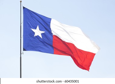 Texas Lone Star Flag Pole Flying Over The Blue Sky .