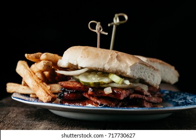 Texas style sausage sandwich with bbq sauce, pickles and onions served with french fries