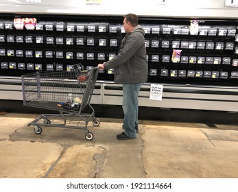 Texas, USA - February 18, 2021: A Caucasian American man wearing winter clothes stands in front of empty meat shelf in a store. The shortage of supply is caused from the unexpected severe snow storm.