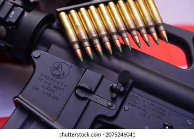 Texas, USA - November 3, 2021: A closeup of M16A2 carbine rifle over the US flag with a stack of ammunition rounds, 5.56 mm caliber. A concept image for gun control and the US military pow