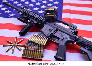 Texas, USA - November 3, 2021: A closeup of Colt M16A2 carbine rifle over the US flag with stacks of ammunition rounds, 5.56 mm caliber. A concept image for gun control and the US military pow