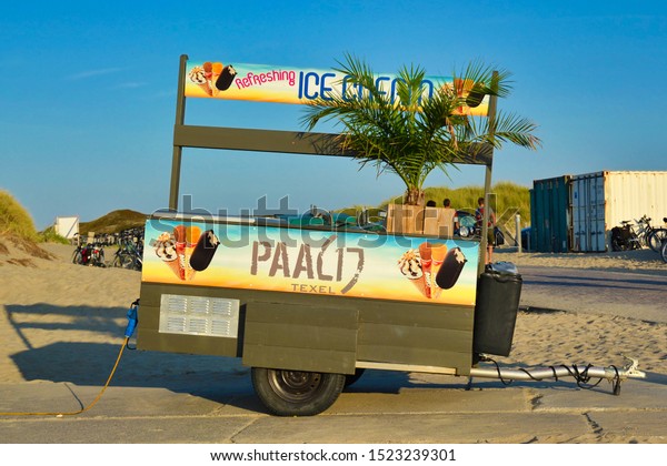 Texel, Netherlands - August 2019: Tropical ice\
cream truck trailer with palm tree  standing at the \'Paal 17\' beach\
of island Texel