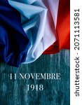 the text 11 novembre 1918, in french, for November 11 1918, the date when was signed the armistice at the end of the World War I, and a french flag on a gray rustic wooden background