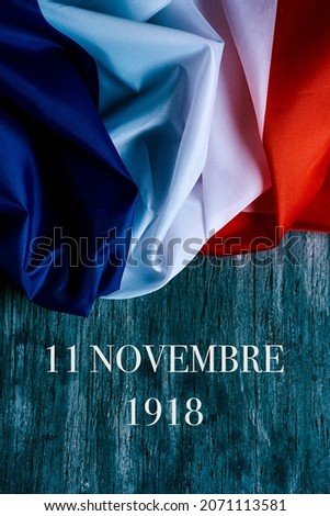 the text 11 novembre 1918, in french, for November 11 1918, the date when was signed the armistice at the end of the World War I, and a french flag on a gray rustic wooden background