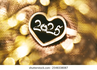 Text 2025 and lipstick kiss, cup of coffee. White cup in shape heart and fluffy scarf, light flares, glittering golden bokeh.Glowing lights. Celebration, holidays and events. Happy New Year  - Powered by Shutterstock