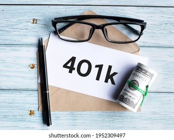 Text 401k written on white paper with a pen,brown envelope,fake money and eye glasses. Finance concept.
