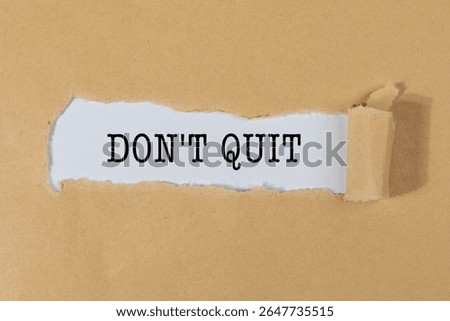 The Text “DON’T QUIT” Appearing Behind Torn Brown Paper – Motivation and Resilience Concept