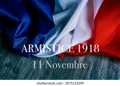 the text armistice 1918 11 novembre, a public holiday held in france on 11 november, that commemorates the armistice at the end of the World War I, and a french flag on a gray rustic wooden background