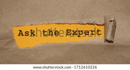 The text ASK AN EXPERT appearing behind torn brown paper. Professional opinion education concept.