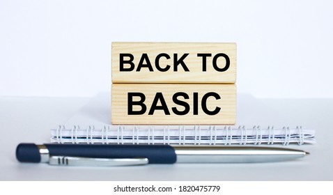 The text BackTo Basic on a bar of wood, lying on a Notepad with a metal blue pen. Business concept photo