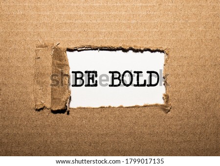 The text BE BOLD. behind torn brown paper