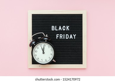 Text Black friday on black letter board and alarm clock on pink background. Concept Black friday , season sales time. Flat lay Top view Copy space Template layout for your design.
