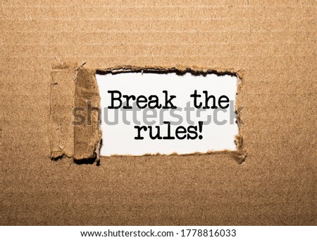 The text BREAK THE RULES behind torn brown paper