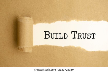 The Text BUILD TRUST Appearing Behind Torn White Paper