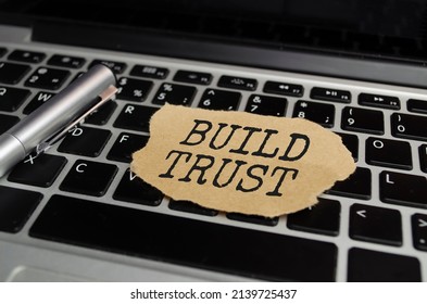 The Text BUILD TRUST Appearing Behind Torn White Paper