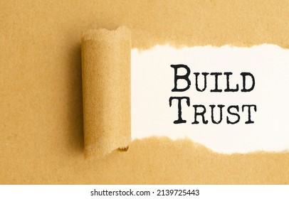 The Text BUILD TRUST Appearing Behind Torn White Paper