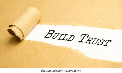 The Text BUILD TRUST Appearing Behind Torn White Paper