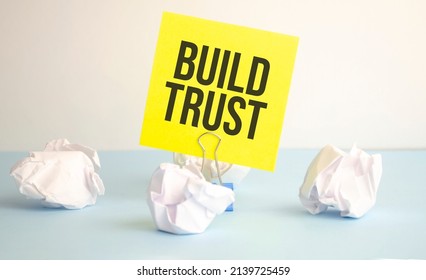 The Text BUILD TRUST Appearing Behind Torn White Paper