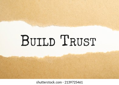 The Text BUILD TRUST Appearing Behind Torn White Paper