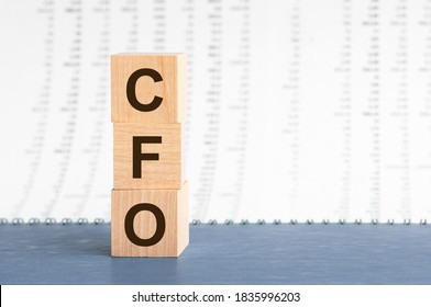 text CFO - Chief Financial Officer on vertical row of wooden blocks on the background of columns of numbers. CFO - Chief Financial Officer acronym on wooden cubes on blue backround. Business concept.