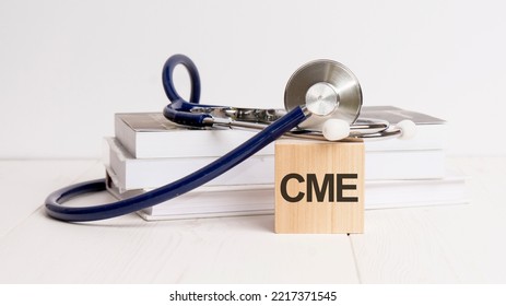 text cme is written on wooden cube near a stethoscope on a white background - Shutterstock ID 2217371545