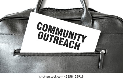 Text COMMUNITY OUTREACH writing on white paper sheet in the black business bag. Business concept - Powered by Shutterstock