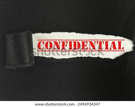 text of confidential on white paper behind the torn black paper. 