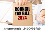 Text COUNCIL TAX BILL 2024 on brown paper notepad in businessman hands on the table with diagram. Business concept