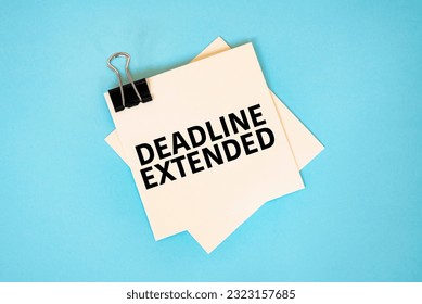 Text DEADLINE EXTENDED on sticky notes with copy space and paper clip isolated on red background.Finance and economics concept.