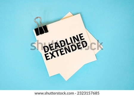 Text DEADLINE EXTENDED on sticky notes with copy space and paper clip isolated on red background.Finance and economics concept.