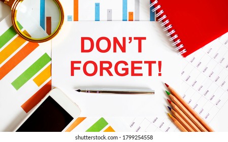 Text DON'T FORGET on notepad with office tools, pen on financial report