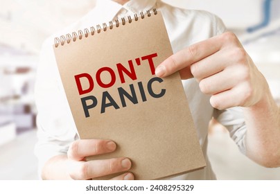 Text DON'T PANIC on brown paper notepad in businessman hands in office. Business concept