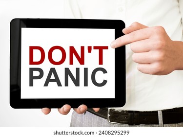 Text DON'T PANIC on tablet display in businessman hands on the white background. Business concept