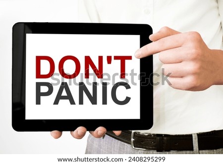 Text DON'T PANIC on tablet display in businessman hands on the white background. Business concept