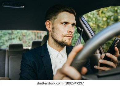 Text and drive. Man using mobile phone while driving the car. Male typing text message on cellphone. An irresponsible dangerous distracted driver. Concentration difficulties overuse social media
