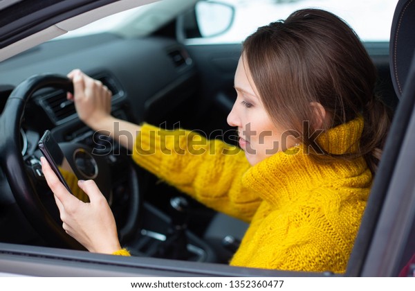 Text and drive woman. A woman is texting on her\
phone while driving
