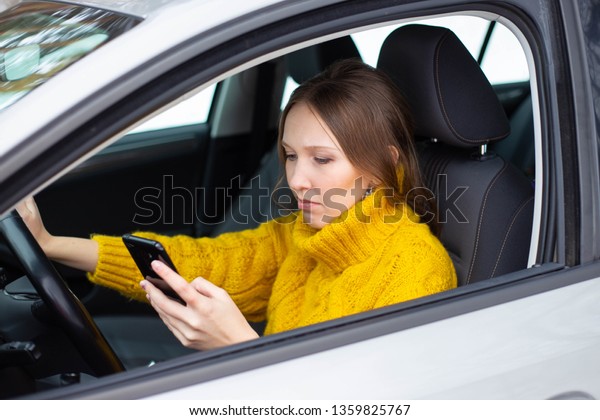 Text and drive woman. A woman is texting on her\
phone while driving