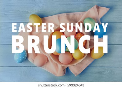 Text EASTER SUNDAY BRUNCH And Colorful Eggs On Blue Wooden Background