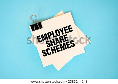Text EMPLOYEE SHARE SCHEMES on sticky notes with copy space and paper clip isolated on red background. Finance and economics concept.