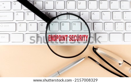 Text ENDPOINT SECURITY on keyboard with magnifier , glasses and pen on a beige background