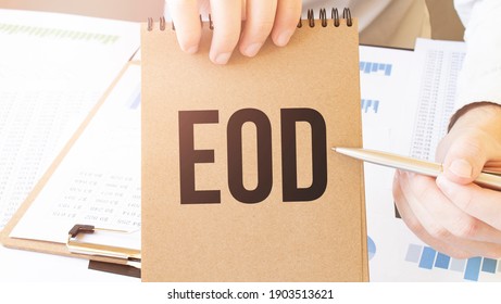 Text EOD on brown paper notepad in businessman hands on the table with diagram. Business concept