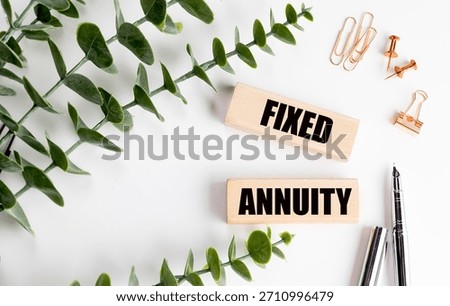 Text fixed annuity written on wooden blocks with green leaves, pens and office supplies on white background. 