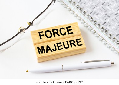 Text Force Majeure On A Wooden Blocks Lying Near Notepad With Eyeglasses And Pen. Could Be For Business, Financial And Marketing Concepts