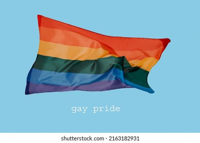 The Text Gay Pride And A Colorful Rainbow Pride Flag Waving In The Air On A Blue Background