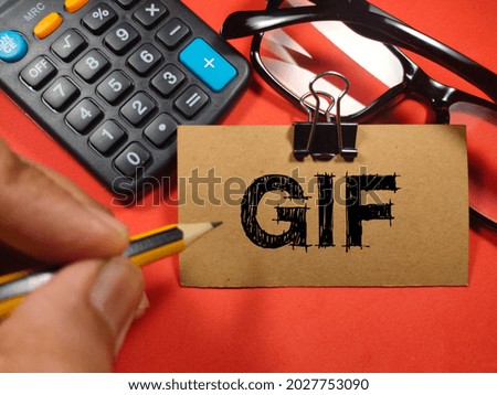 Text GIF (Graphics Interchange Format) writing on brown card with hand holding pencil,calculator and glasses on red background.