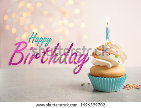 Text Happy Birthday and delicious cupcake with candle on blurred background