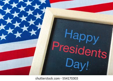 the text happy presidents day written in a chalkboard and a flag of the United States - Shutterstock ID 554170303