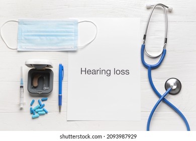 Text HEARING LOSS With Stethoscope, Medical Mask And Aid On White Wooden Background